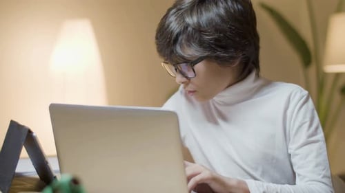 Smart Schoolboy Working on Laptop in the Evening at Home