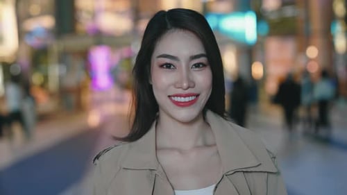Retrato de uma linda garota sorridente de aparência asiática em pé no meio da cidade noturna