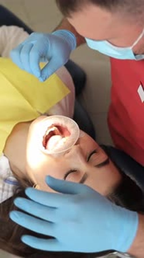 Dentista usa extensor de borracha para um paciente em vídeo vertical de clínica odontológica moderna