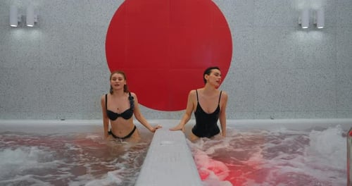 Hermosas amigas que pasan el fin de semana en el spa relajándose en el jacuzzi con agua burbujeante