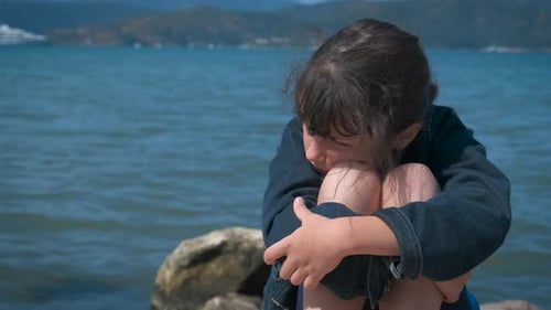 Sad Child Sitting Near the Ocean