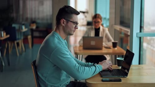 Man Working On Laptop in Urban Cafe