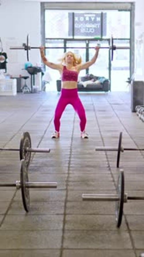 Strong Athletic Woman Lifting Heavy Barbell in a Gym