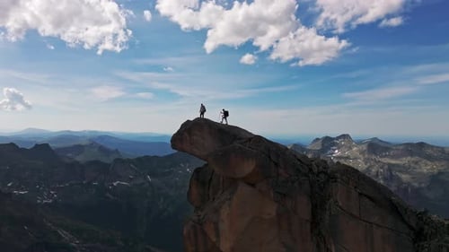 Two Hikers Reach Summit of Mountain Peak on Sunny Day