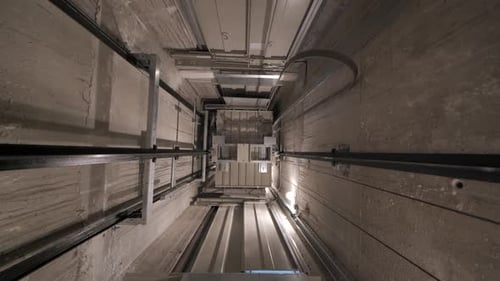 Elevator lift cabin moves up inside illuminated elevator shaft with hydraulics with many floors slow