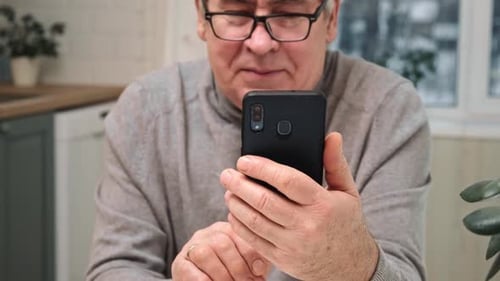 Senior Man Using Smartphone Indoors at Home
