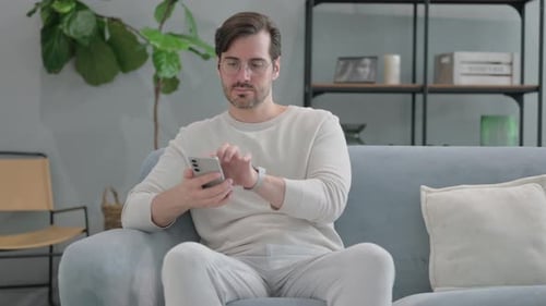 Man Using Mobile Phone While Sitting on Couch