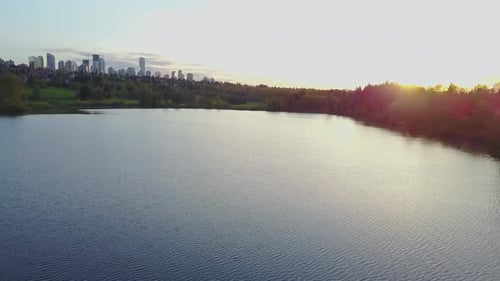 Aerial Footage of a Lake in the City Park During a Colorful and Vibrant Sunset with Red Color Sky