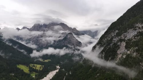 Drone aerial view of clouds drifting over the majestic peaks of the Alps mountains