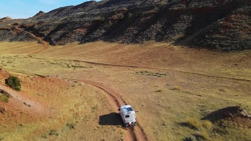 van driving out of 4x4 trails in a red arid expanse.