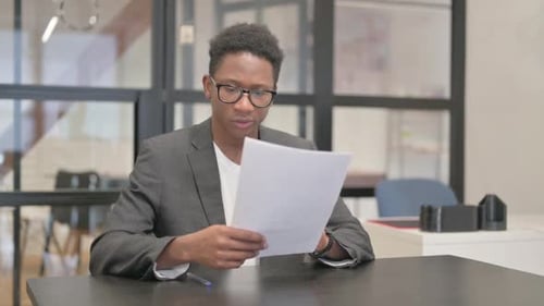 Young Adult Reviews Documents at Office Desk