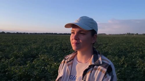 Smiling Woman Farmer in Agricultural Field at Golden Sunset