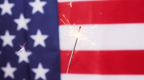 Sparkler Burning Brightly Against American Flag Backdrop