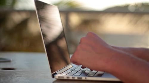 Young man working on laptop at sunrise on a beautiful beach location
