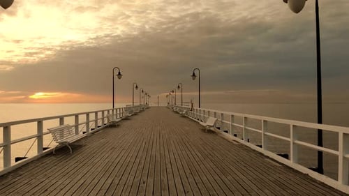 Slow passage over a wooden pier at sunrise. Empty bridge at sunrise. Orange sky on the horizon and c