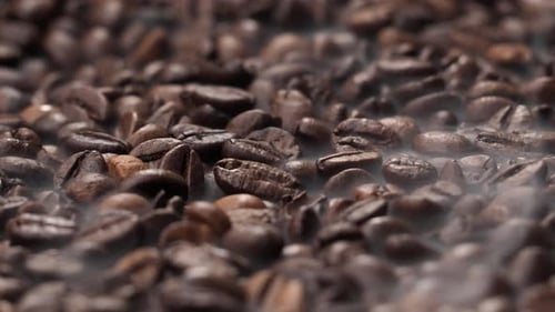 Roasted coffee beans. The smoke comes from fresh coffee seeds.