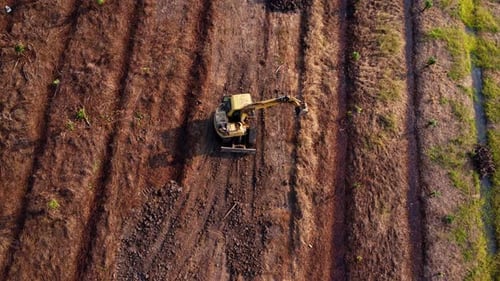 Aerial view of a wheel loader excavator with a backhoe loading sand into a heavy earthmover