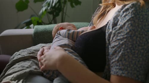 Madre joven amamantando a un bebé somnoliento