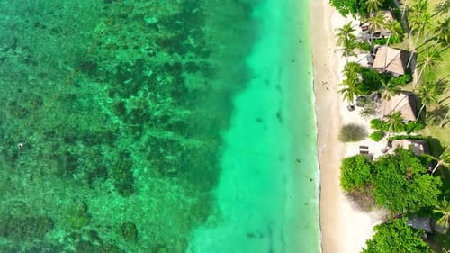 Sandy beach shore with beautiful resort surrounded by clear sea water.