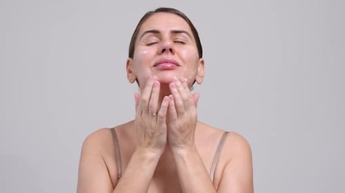 Woman Applies Lotion to Her Face and Neck
