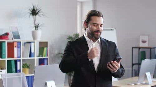 Male with Phone Doing Winner Gesture at Business Center