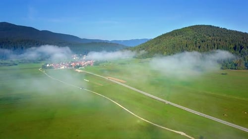 Mountain landscape. Fragment of a village at dawn, in the morning fog. Shooting from a drone.
