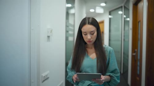 Woman Ceo Browsing Tablet Computer in Office. Busy Manager Walking Through Corridor