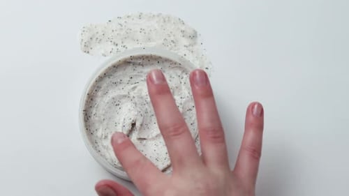 Woman Applying Exfoliating Face or Body Scrub on Hand Skincare Routine with Natural Cosmetic Cream