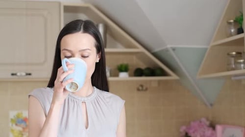 Woman Drinking Coffee in Kitchen
