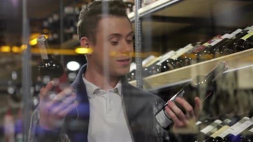 Man Choosing Between Wine Bottles in Store