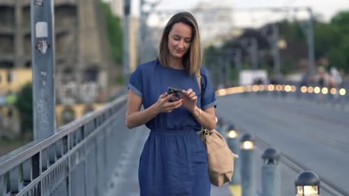 Young woman texting on smartphone during evening walk in the city slow motion