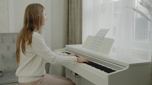 Young Woman Plays Piano at Home Near Window