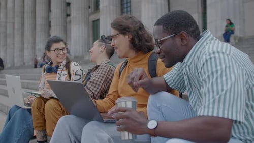 Group of Students Using Laptops and Chatting on Stairs Outside University