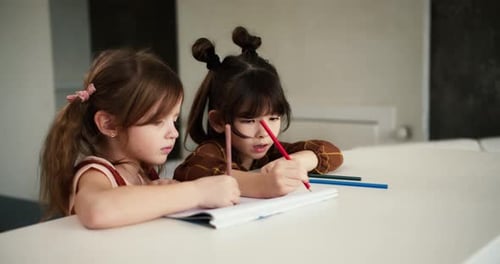 Zwei kleine Kinder am Tisch zeichnen mit Buntstiften