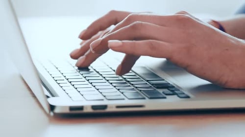 Hands Typing on Laptop Keyboard in Office
