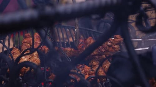 Vendor Flipping Grilled Chicken on Open Flame