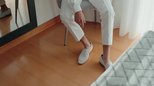 Man Puts on Loafers in Bedroom
