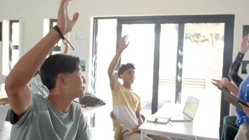 In high school, students raising hands in classroom, participating in discussion