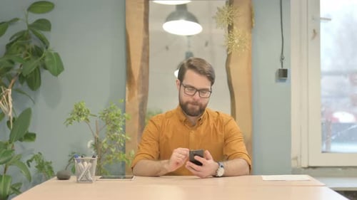 Man Celebrating Success While Looking at Phone