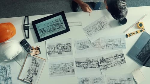 Ansicht von oben auf den Ingenieur, der auf das Tablet schaut, während er auf den Laptop schaut. Ernährung.
