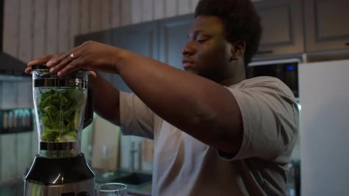 Black Man Using Kitchen Blender for Making Healthy Green Smoothie
