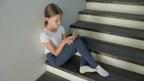 Girl Sits on Stairs Using Mobile Phone