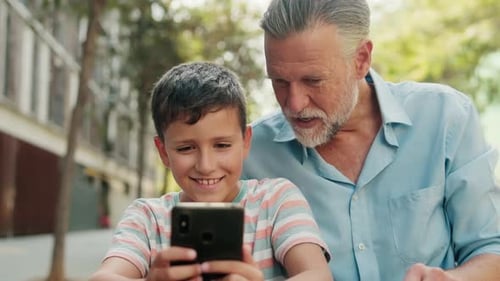 Boy and Senior Man Using Smartphone Together