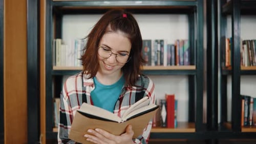 Young Woman Student Reading a Book in the Library Sitting on the Floor Students in a Good Mood