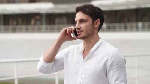 Confident businessman in suit discussing business on smartphone outdoors in the city