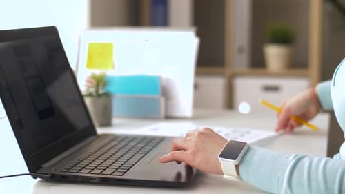 Mulher criativa projeta interface de usuário em laptop com smartwatch em escritório moderno