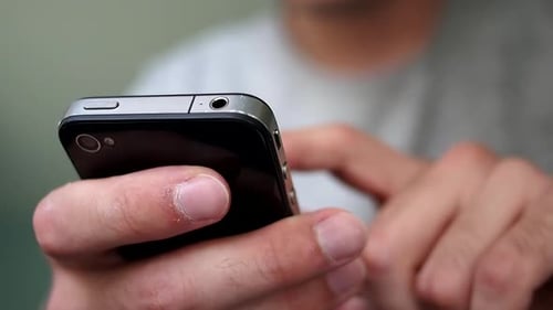 Synergy Collection: Close-up view of a mobile phone's rear with a man operating