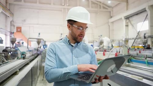 Industrial Programmer Checking the Conveyor with Laptop Computer