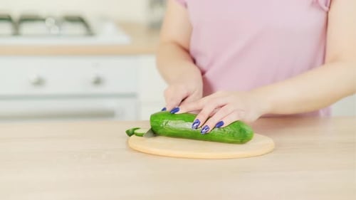 Woman Slicing Cucumber in Clean Kitchen
