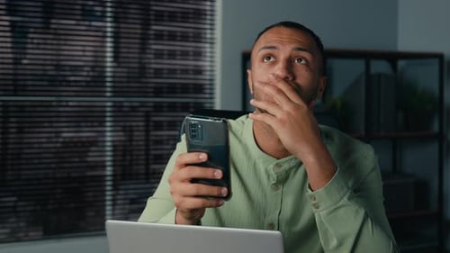 Worried Man Looking at Smartphone in Office